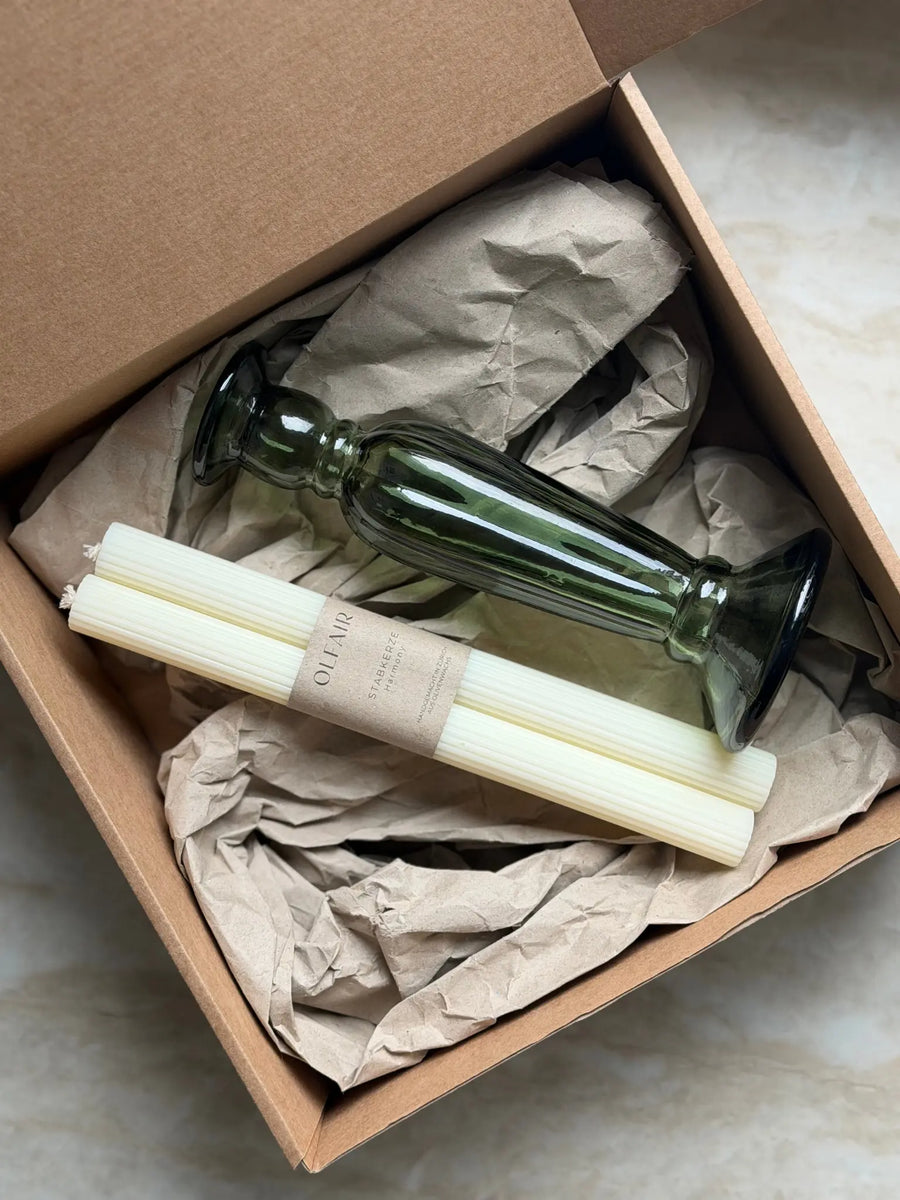 Geschenkset bestehend aus einem 2er-Set Stabkerzen mit kleinen Rillen und einem grünen Kerzenhalter aus Recycling-Glas