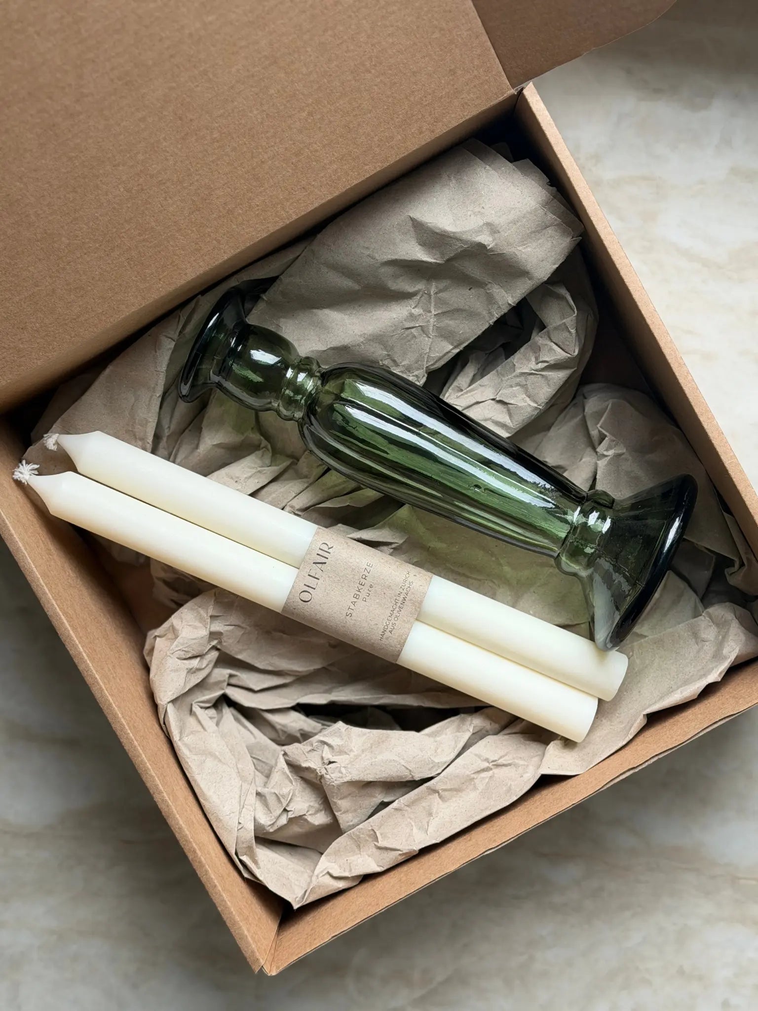 Geschenkset bestehend aus einem 2er-Set glatten Stabkerzen und einem grünen Kerzenhalter aus Recycling-Glas