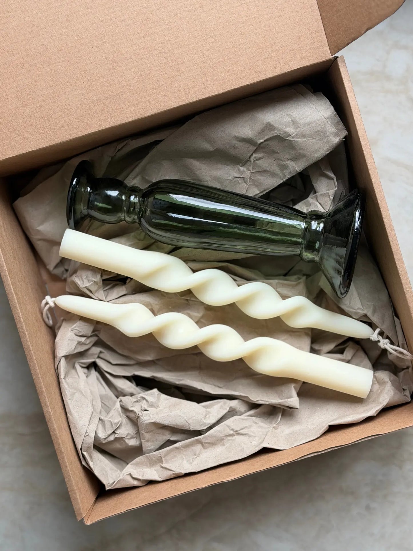 Geschenkset bestehend aus einem 2er-Set kleiner, gedrehter Stabkerzen und einem grünen Kerzenhalter aus Recycling-Glas