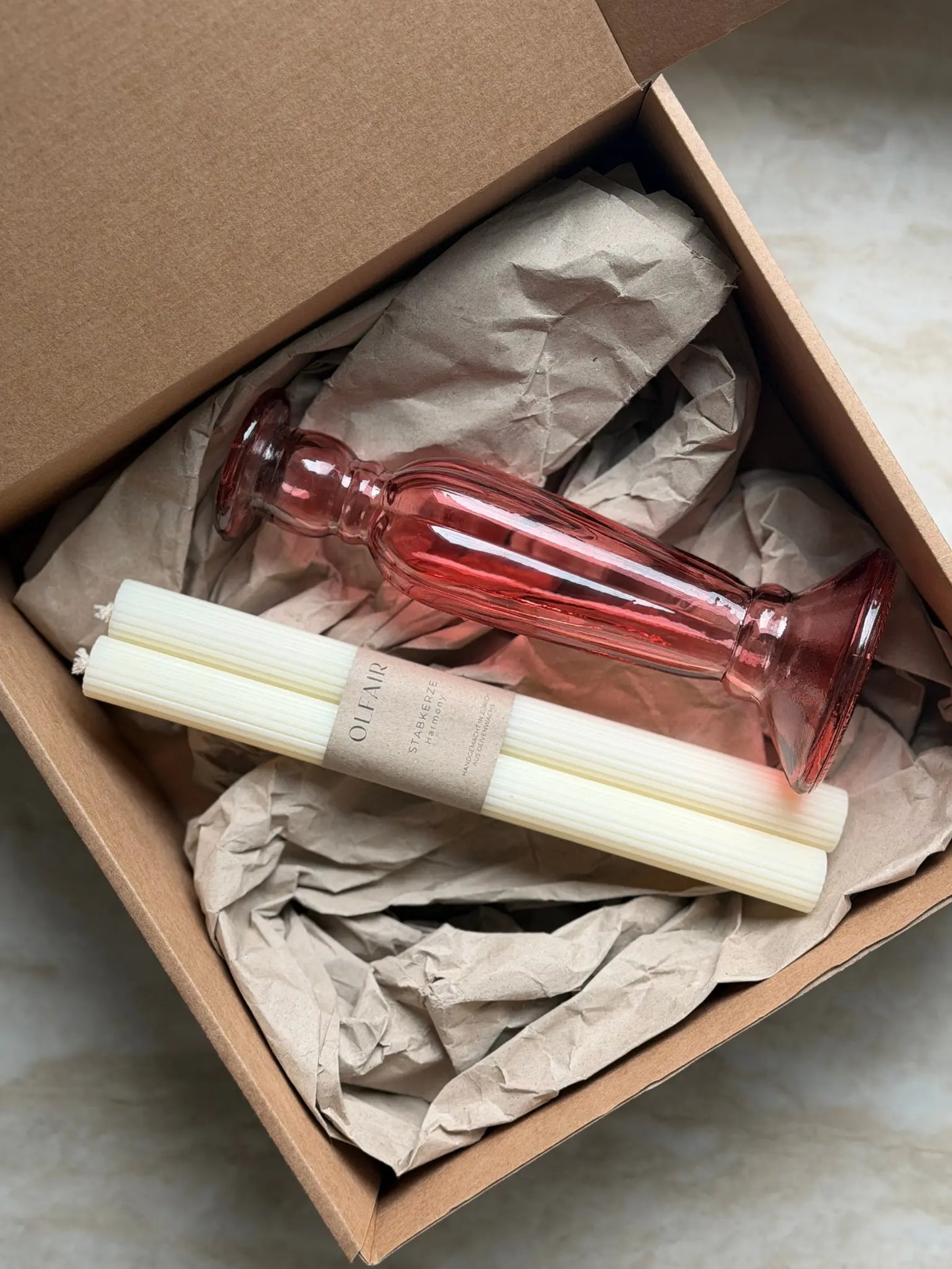Geschenkset bestehend aus einem 2er-Set Stabkerzen mit kleinen Rillen und einem rosa Kerzenhalter aus Recycling-Glas