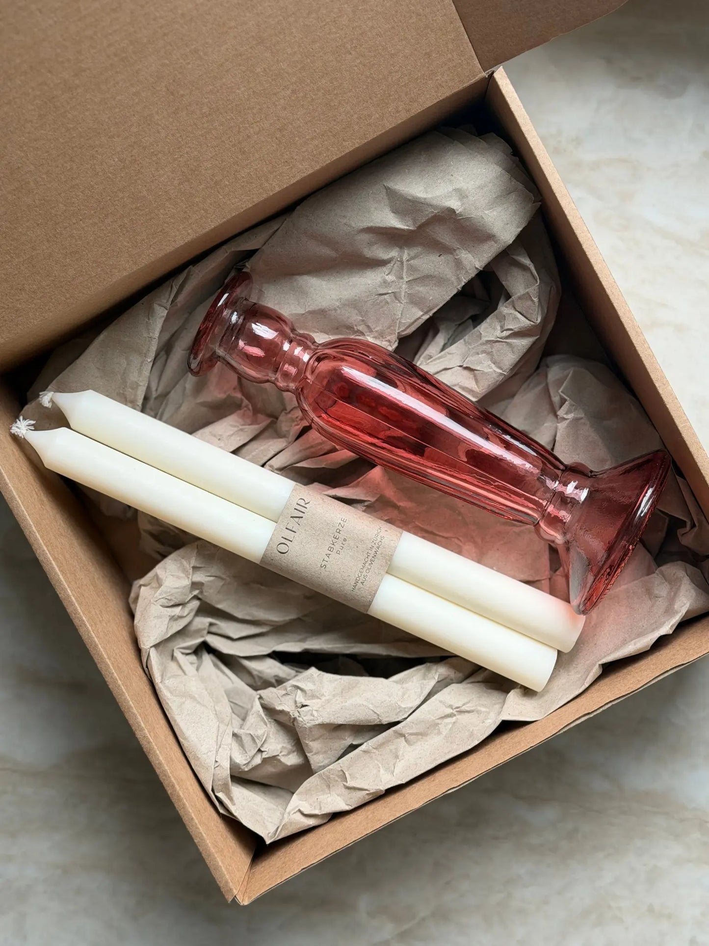 Geschenkset bestehend aus einem 2er-Set glatten Stabkerzen und einem rosa Kerzenhalter aus Recycling-Glas