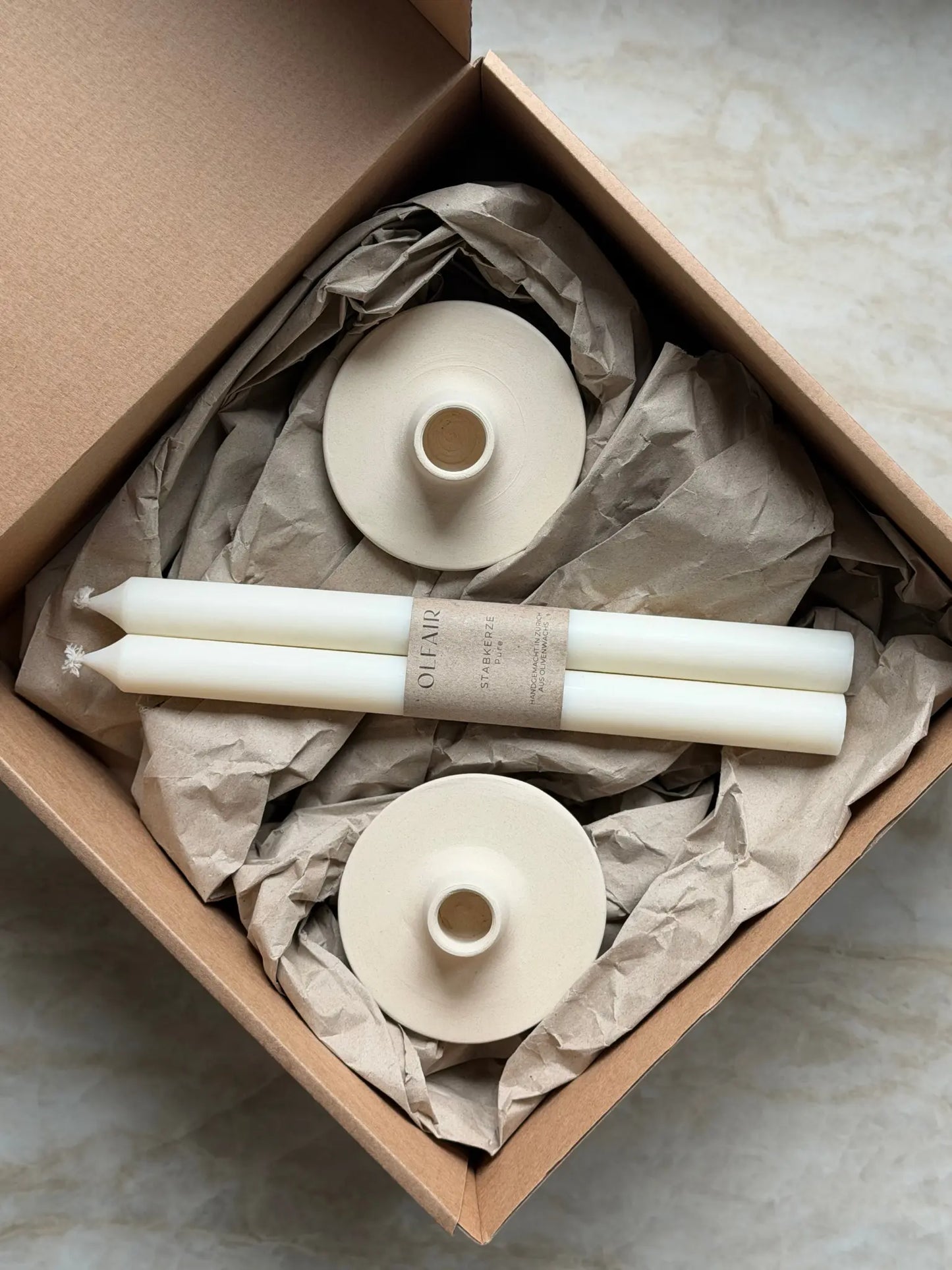 Geschenkset bestehend aus einem 2er-Set glatter Stabkerzen und zwei Kerzenhalter aus Keramik.
