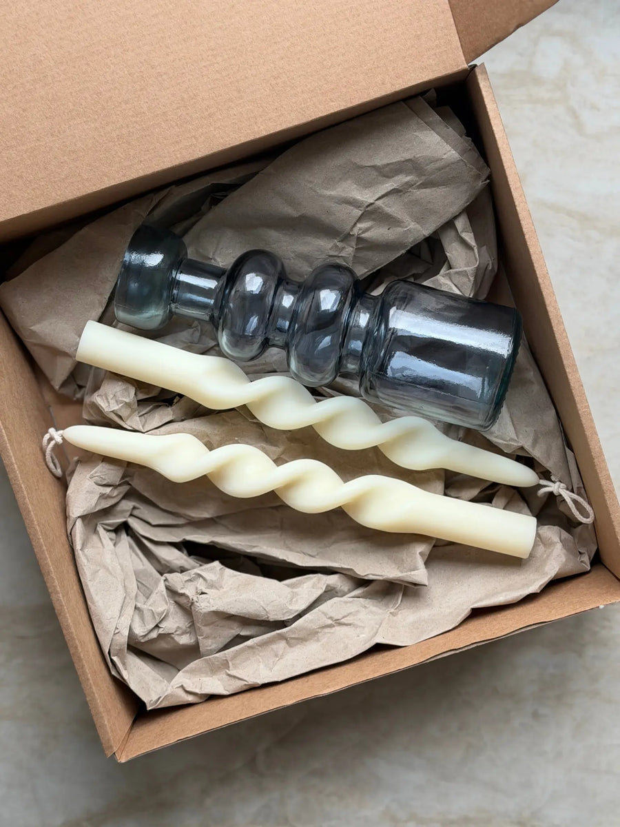 Geschenkset bestehend aus einem 2er-Set gedrehten Stabkerzen und einem Kerzenhalter in blau aus Recycling-Glas.