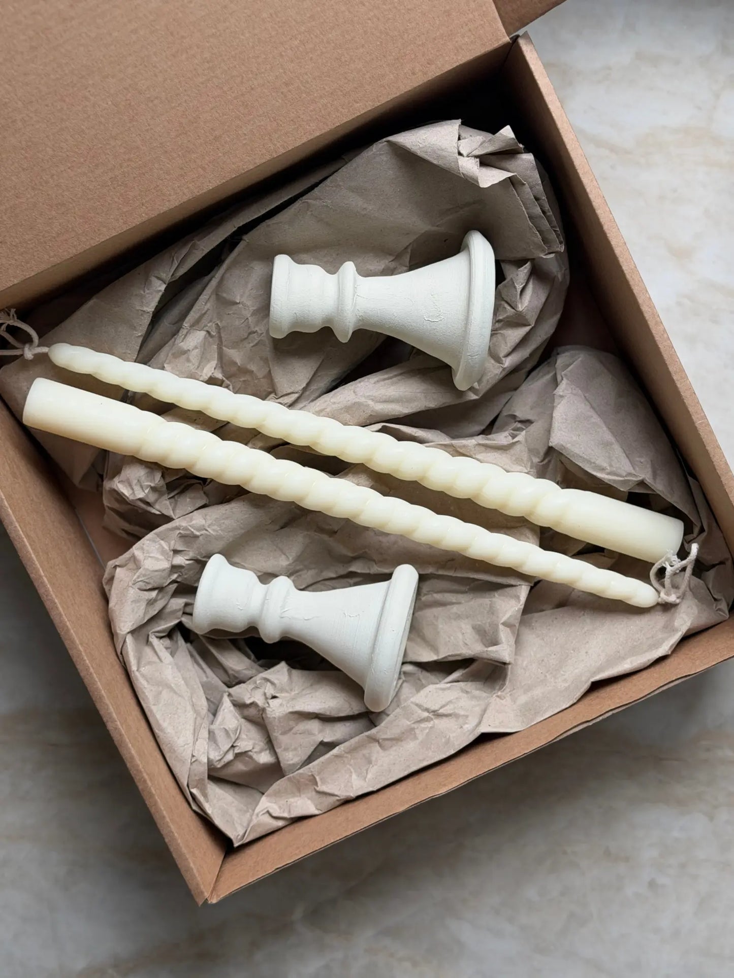 Geschenkset bestehend aus einem 2er-Set leicht gedrehter Stabkerzen und zwei Kerzenhalter aus Keramik.