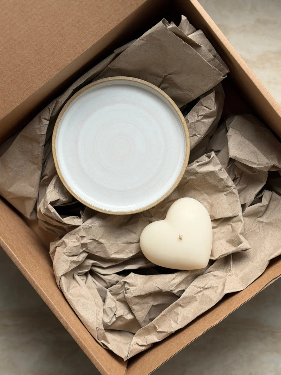 Geschenkset mit einer Herzkerze und einem Kerzenteller aus Keramik in einer Kartonbox.