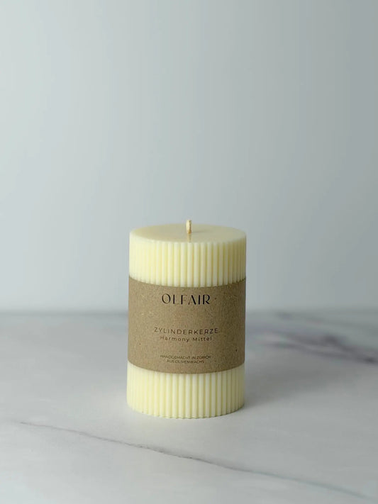 Mittelgrosse Zylinderkerze mit kleinen Rillen vor einem Marmor Hintergrund.