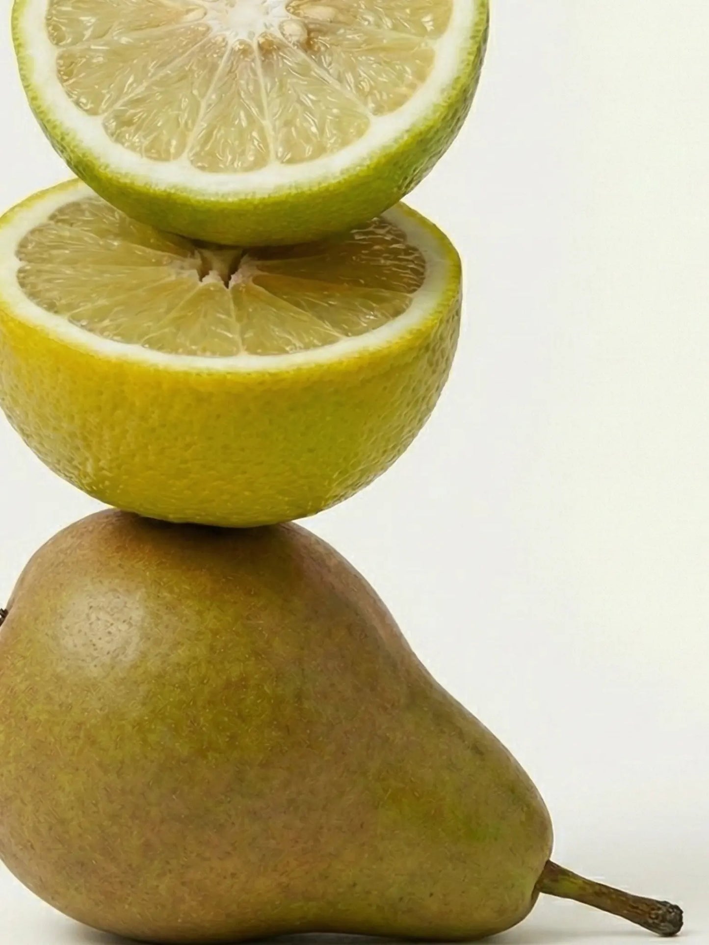 Birne und zwei aufgeschnittene Bergamotten vor einem hellen Hintergrund.