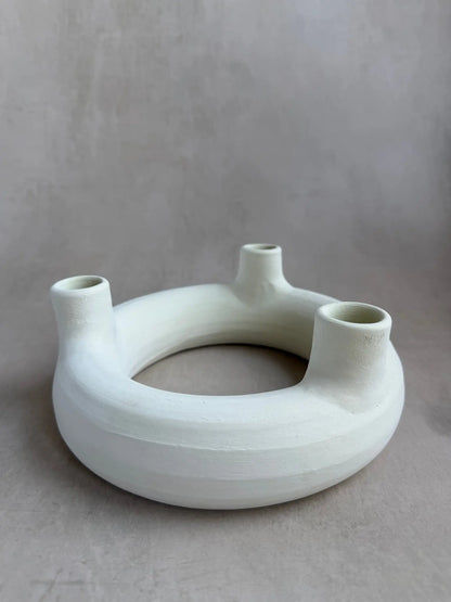 Runder Kerzenhalter mit Löchern für drei Kerzen aus unglasierter Keramik in off-white.