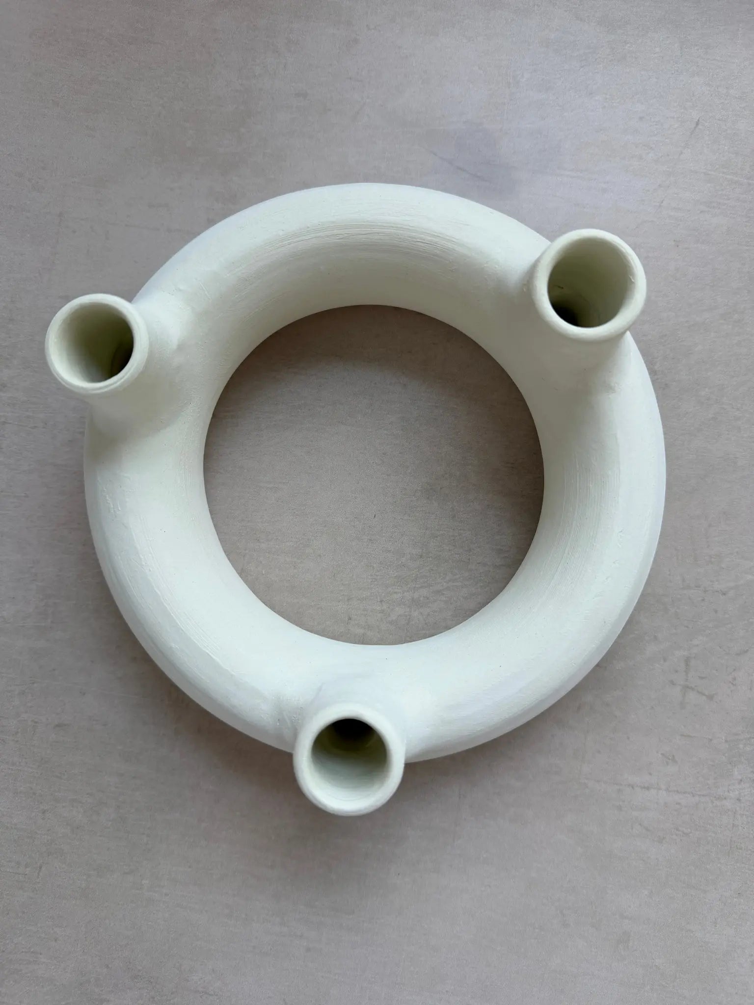Runder Kerzenhalter mit Löchern für drei Kerzen aus unglasierter Keramik in off-white von oben.