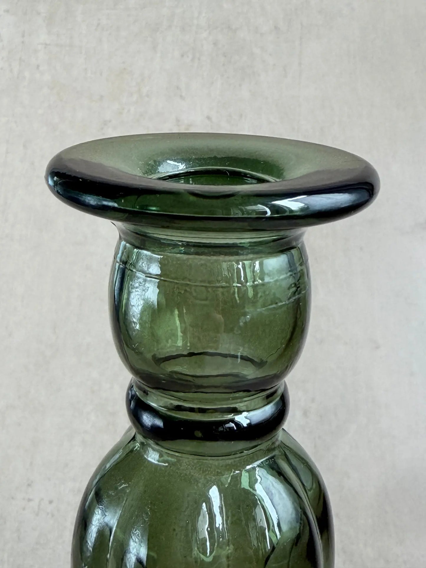 Nahaufnahme eines grünen Kerzenhalters aus Recyclingglas auf einem beigen Hintergrund.