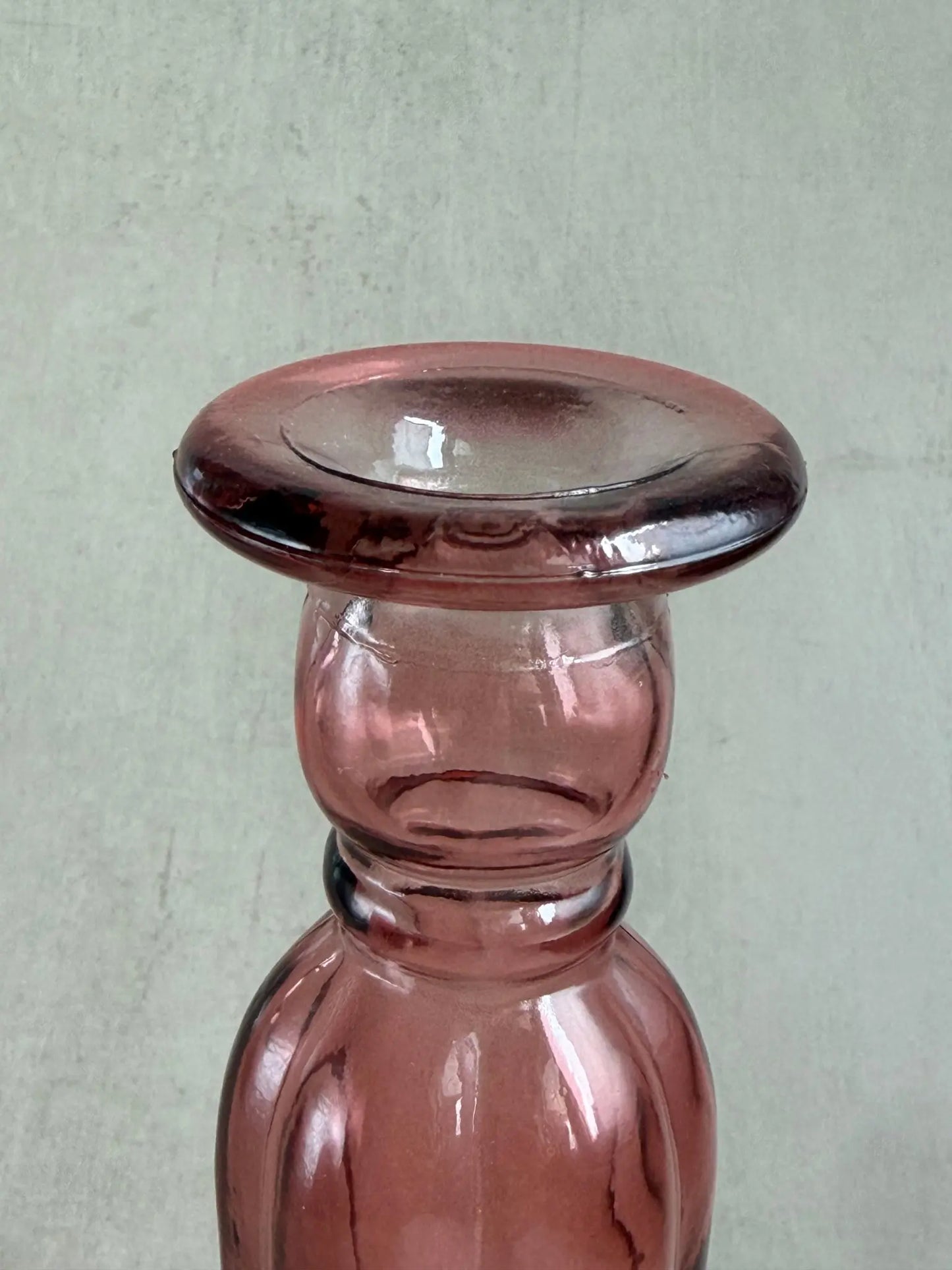 Nahaufnahme eines rosafarbigen Kerzenhalters aus Recyclingglas auf einem beigen Hintergrund.