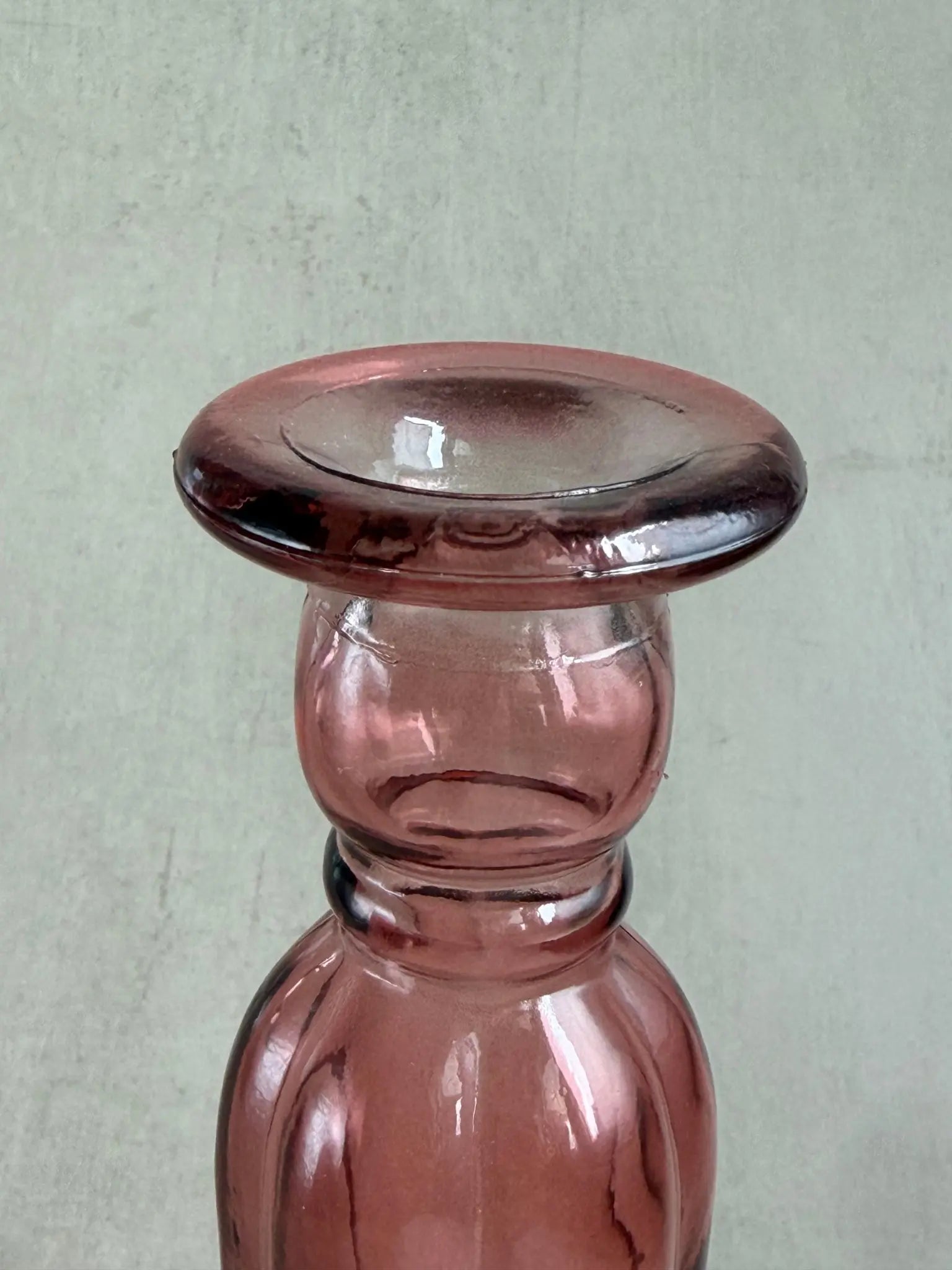 Nahaufnahme eines rosafarbigen Kerzenhalters aus Recyclingglas auf einem beigen Hintergrund.