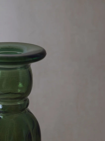 Teilaufnahme eines grünen Kerzenhalters aus Recyclingglas auf einem beigen Hintergrund.