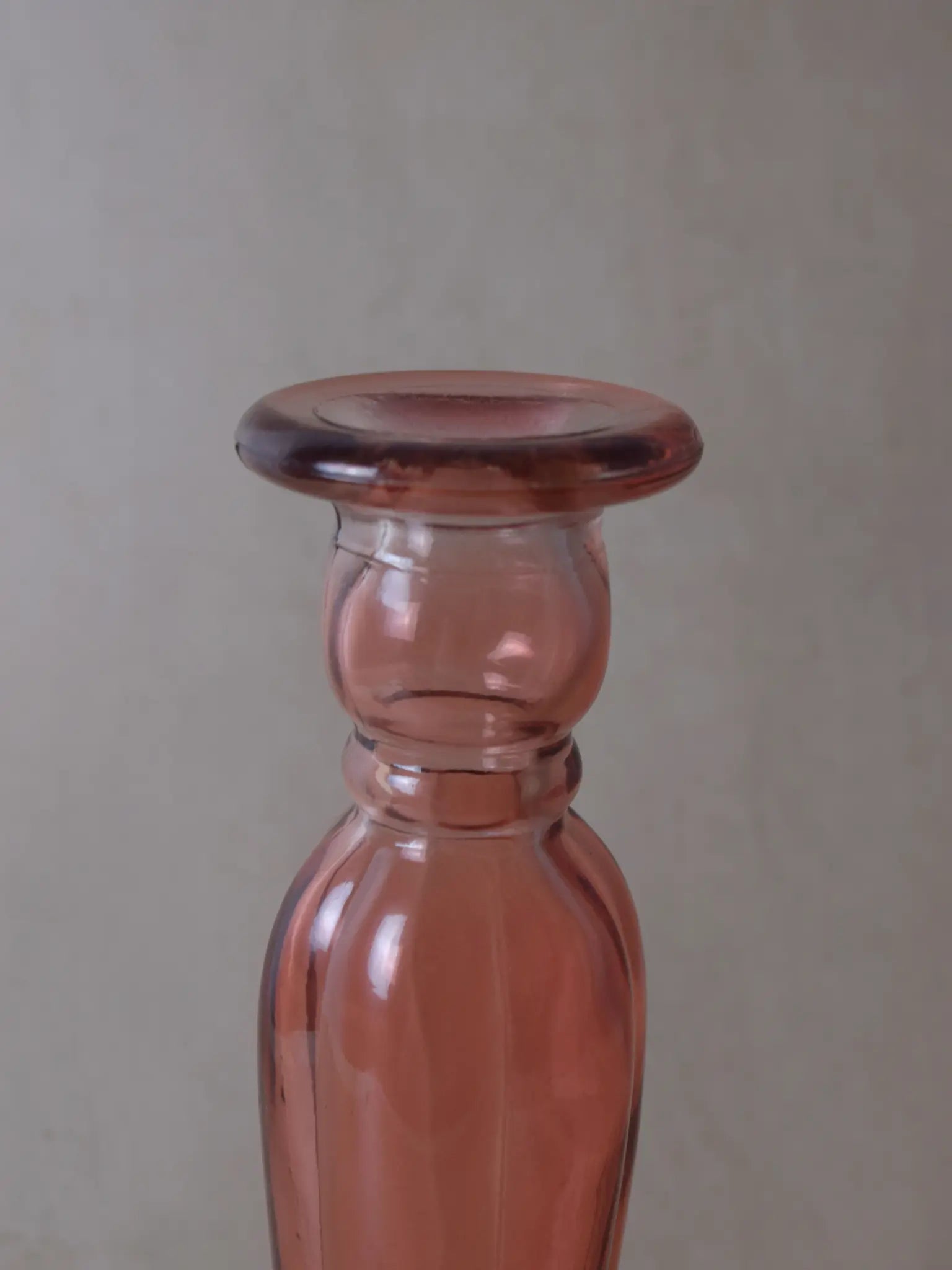 Nahaufnahme eines rosafarbigen Kerzenhalters aus Recyclingglas auf einem beigen Hintergrund.