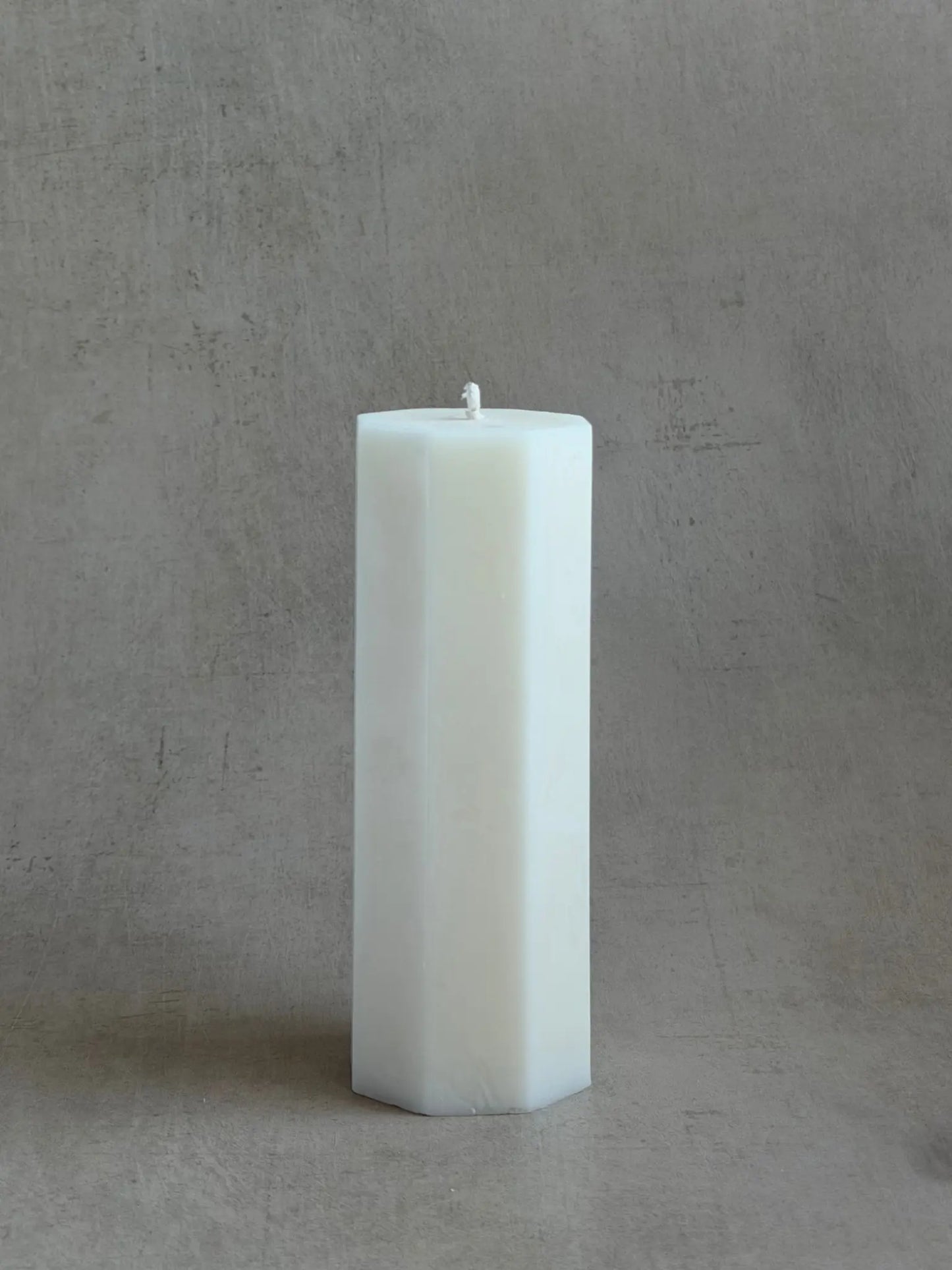 Achteckige Zylinderkerzen vor einem beigen Hintergrund