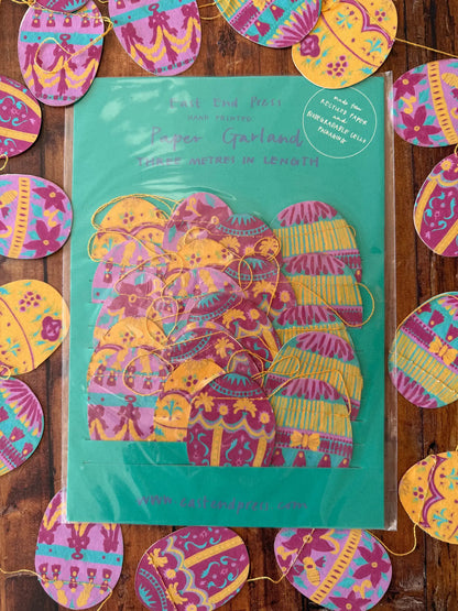 Verpackte Girlande mit Ostereier. Eine Ostereier Girlande liegt umd die Verpackung.