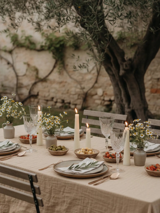 Gedeckter Sommertisch mit Tapas und Vulcano Kerzen. Im Hintergrund ist ein grosser Olivenbaum zu sehen.