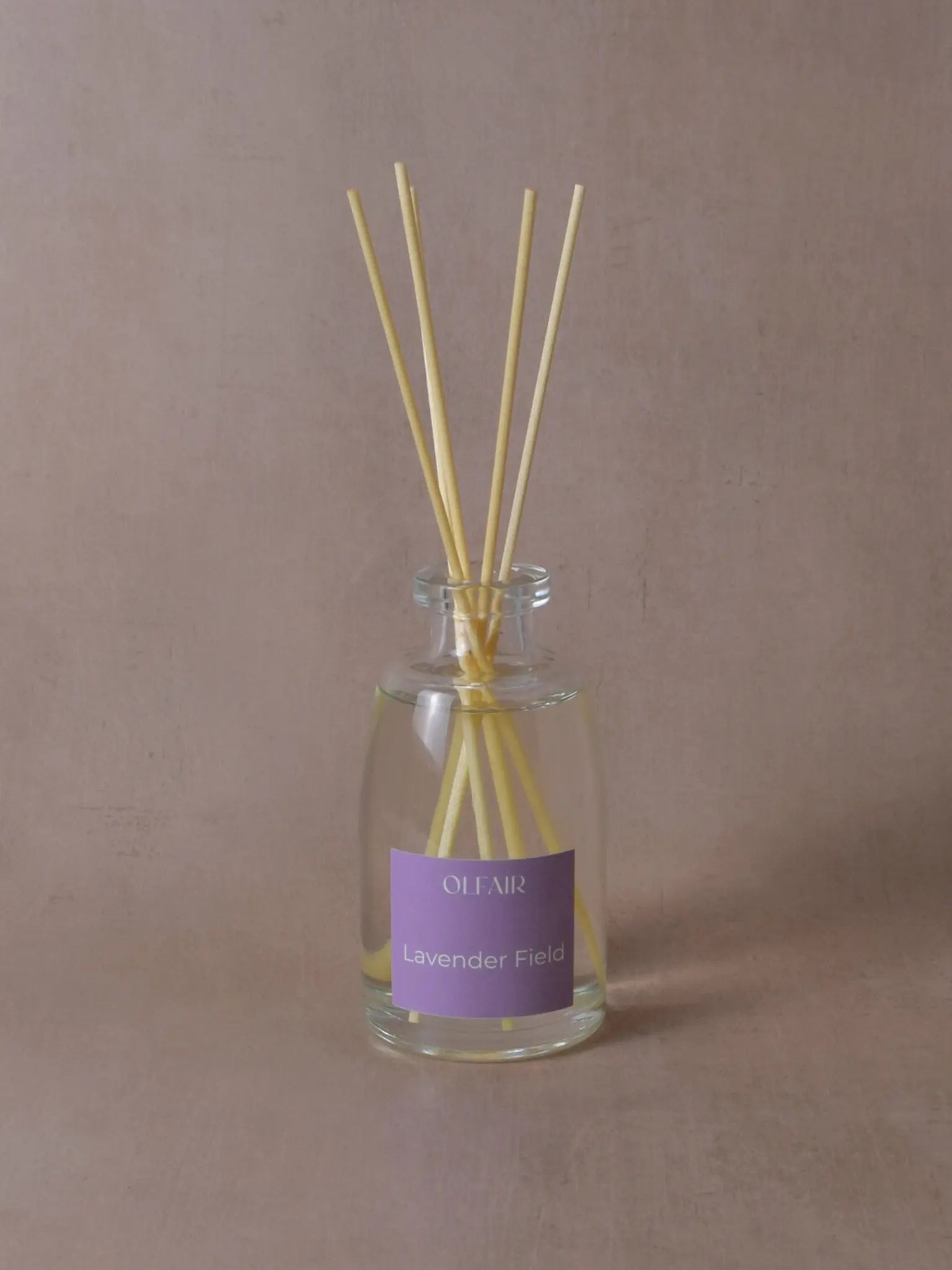Grosser Raumduft mit Stäbchen und einem violetten Etikett vor einem beigen Hintergrund.