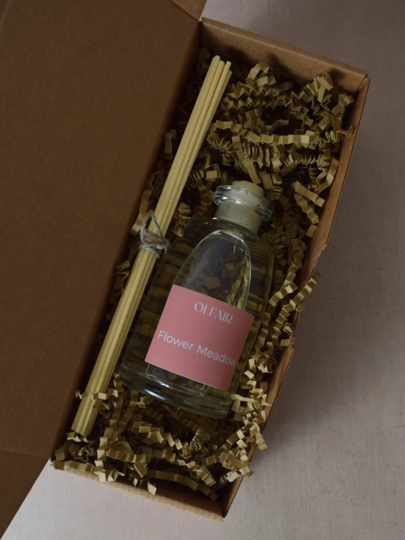 Raumduft mit dunkel rosa Etikette mit Stäbchen in einer Box.