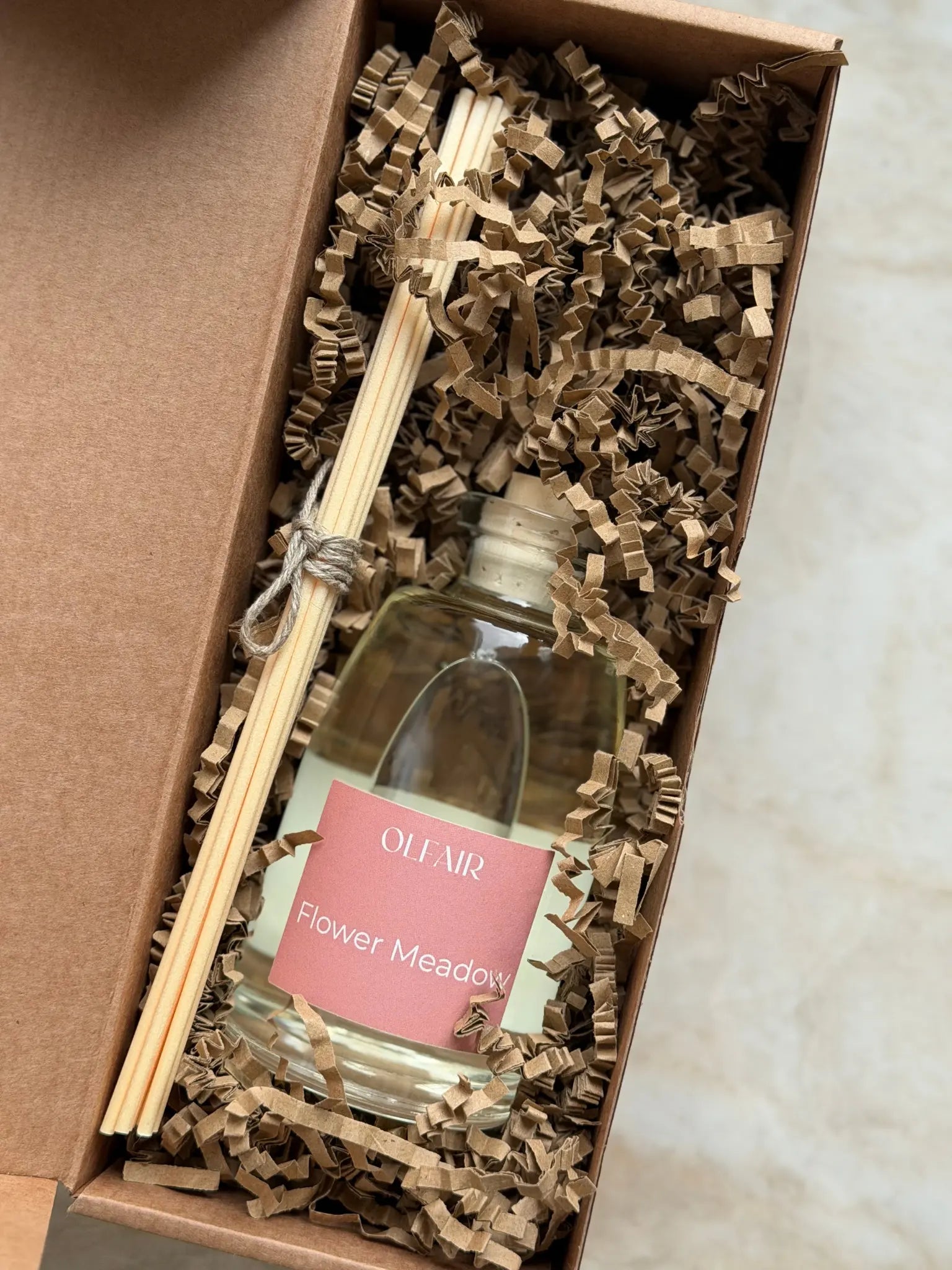 Raumduft mit dunkel rosa Etikette mit Stäbchen in einer Box.