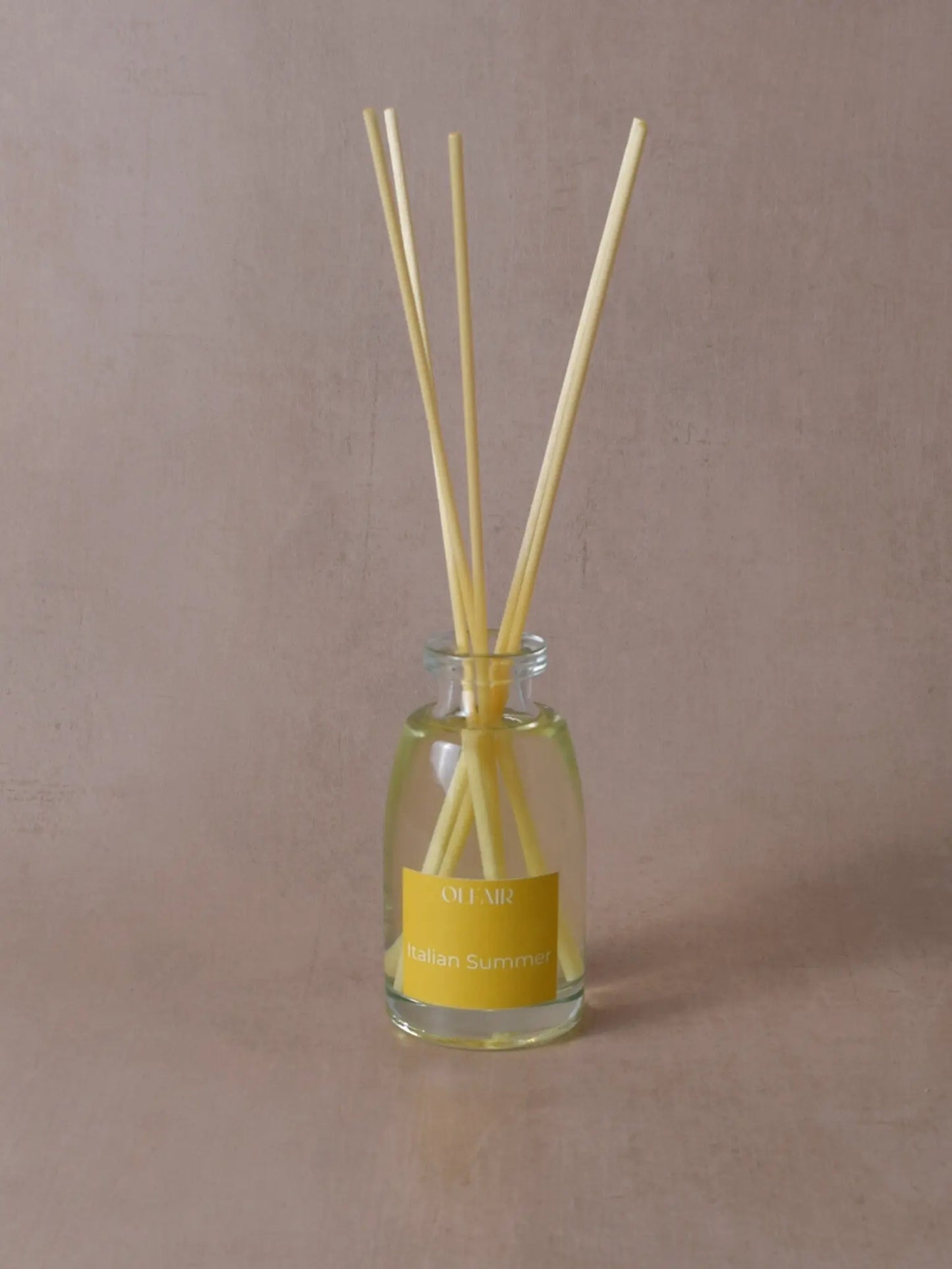 Kleiner Raumduft mit Stäbchen und einem gelben Etikett vor einem beigen Hintergrund.