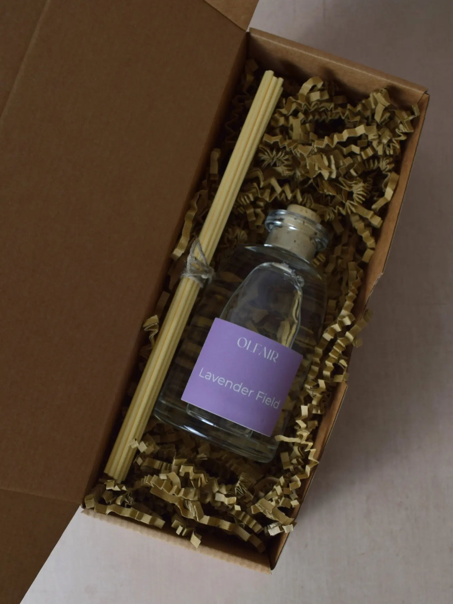 Raumduft mit violettem Etikette mit Stäbchen in einer Box.