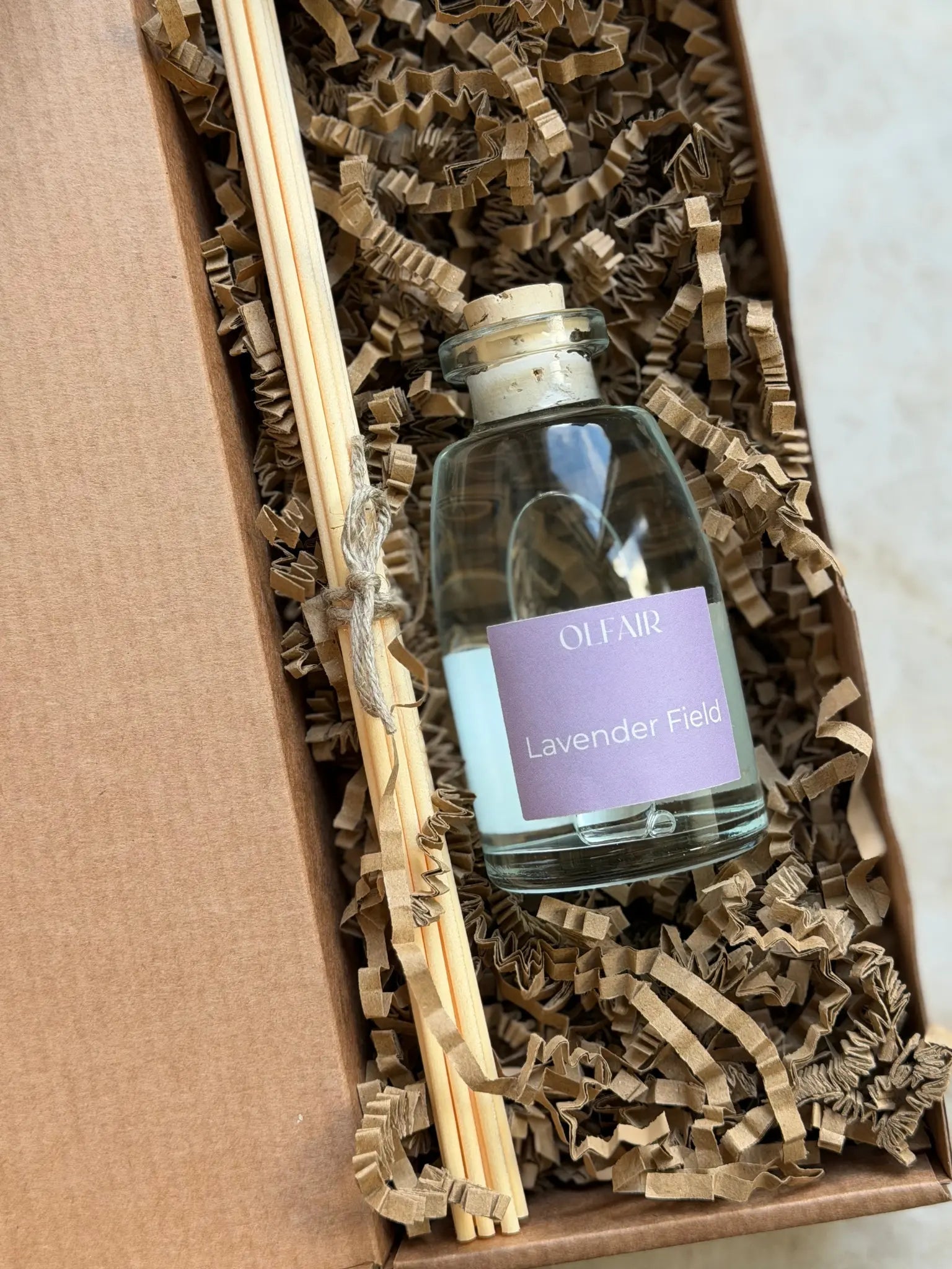 Raumduft mit violettem Etikette mit Stäbchen in einer Box.