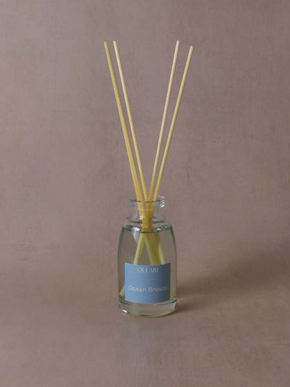 Kleiner Raumduft mit Stäbchen und einem ozeanblauem Etikett vor einem beigen Hintergrund.