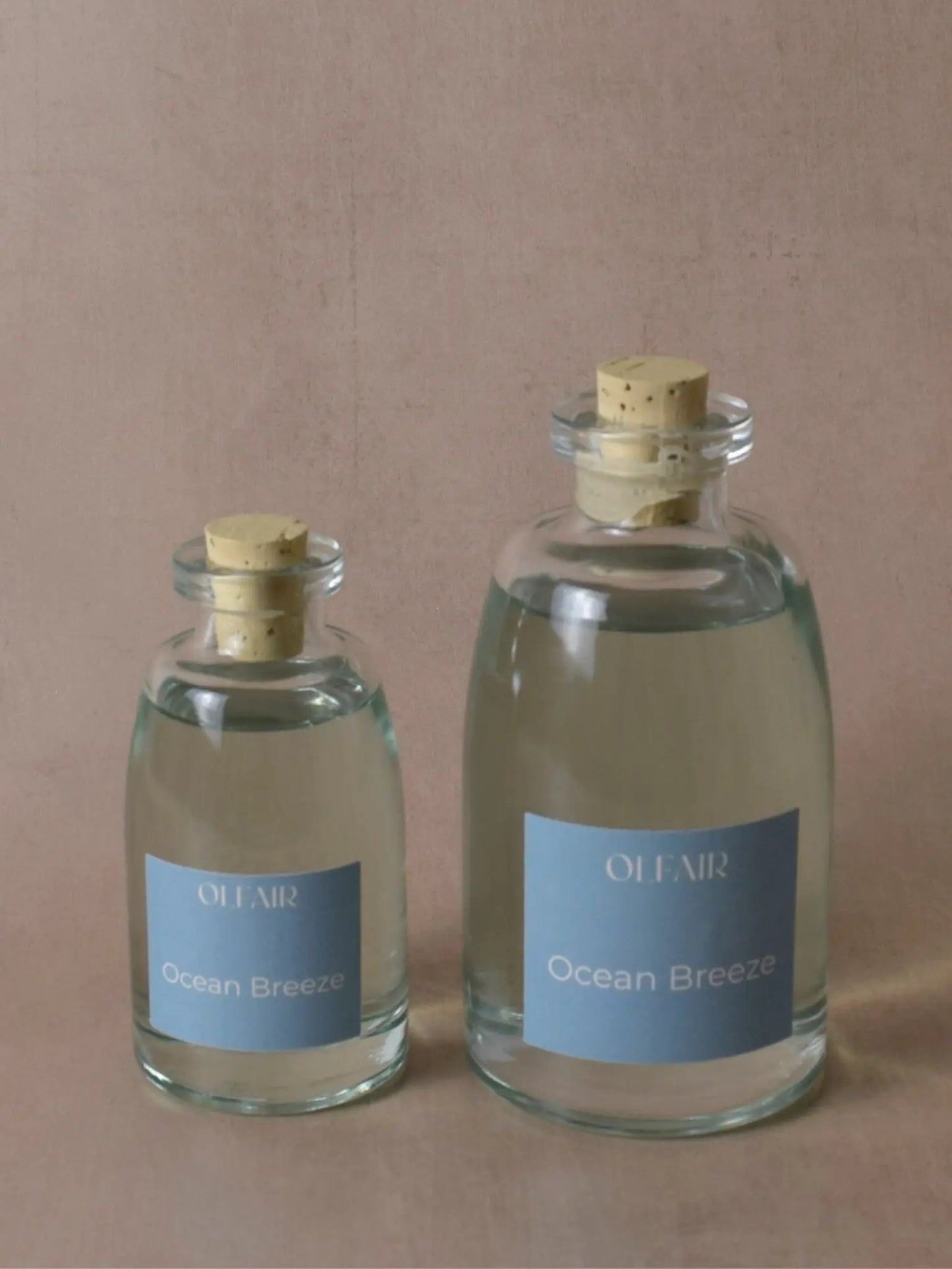 Kleiner und grosser Raumduft mit einem ozeanblauen Etikett vor einem beigen Hintergrund.