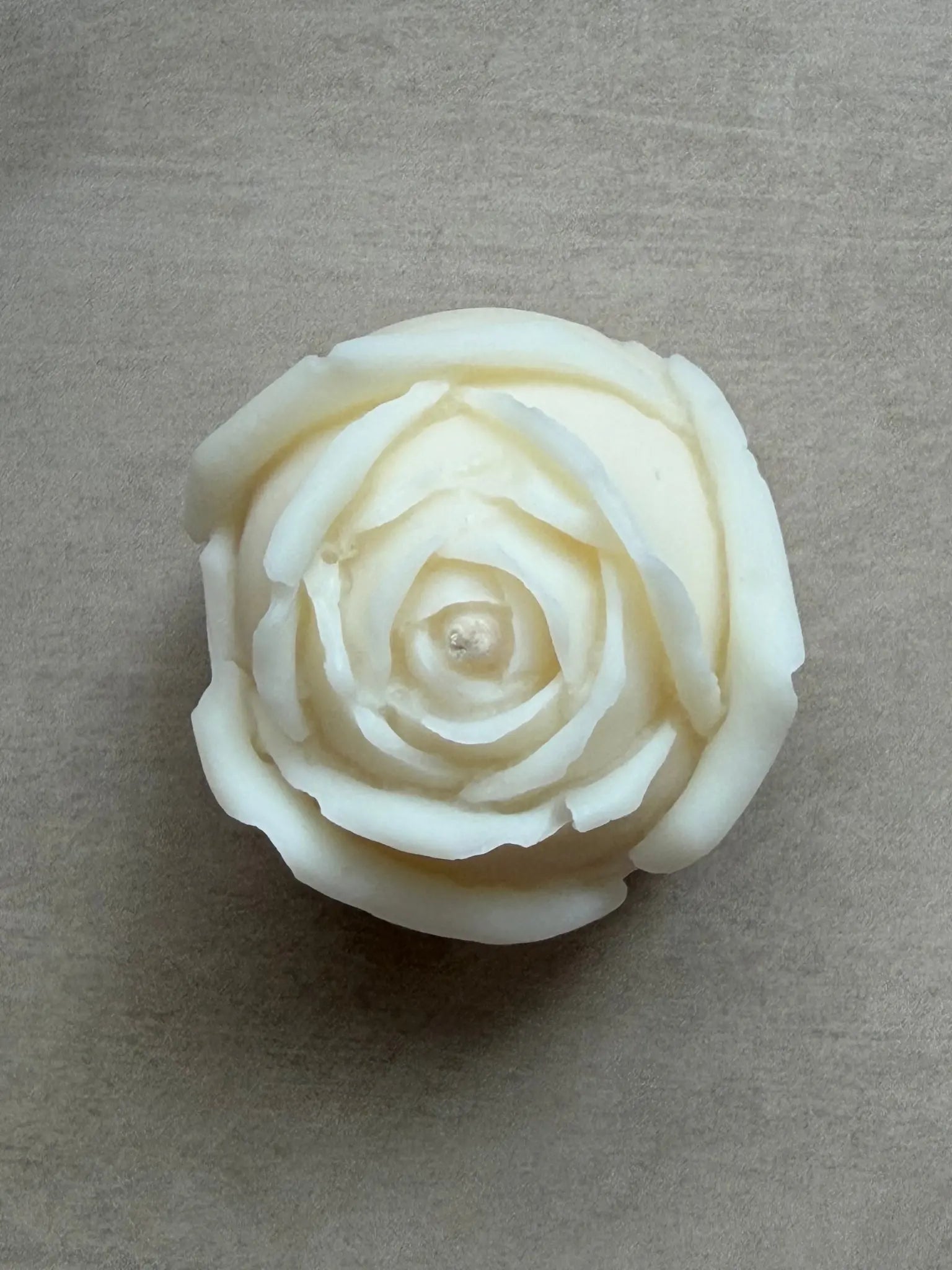 Rosenkerze in naturweiss von oben auf einem beigen Hintergrund