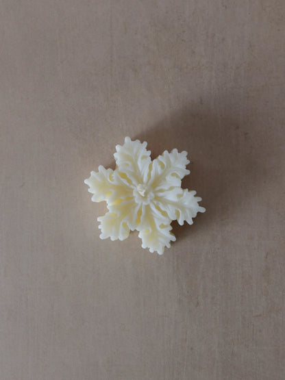 Naturfarbene Kerze in Schneeflockenform.