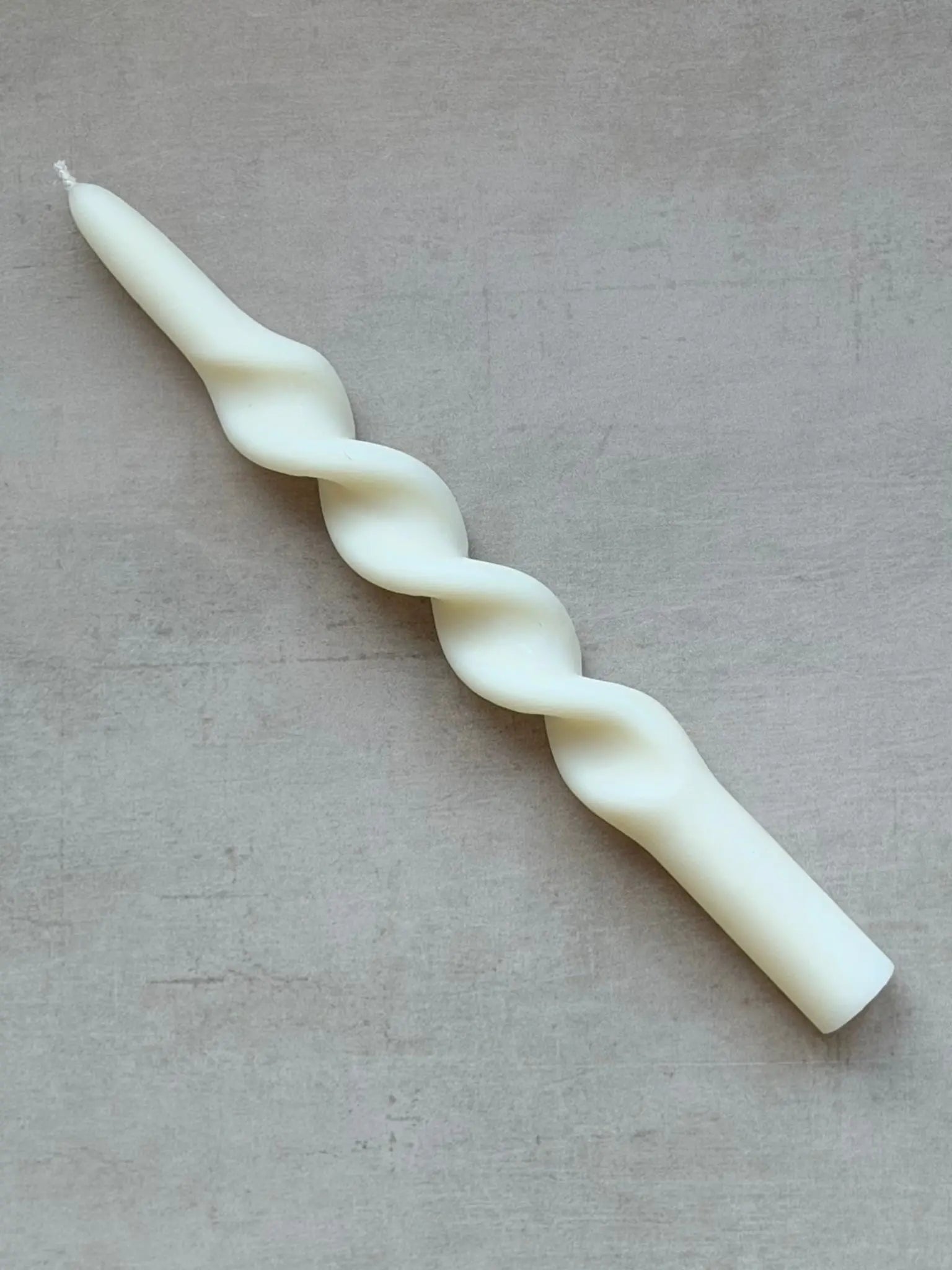Grosse, gedrehte Stabkerze auf einem Marmor Hintergrund.