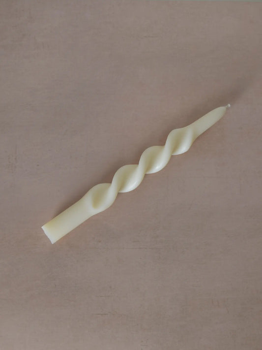 Gedrehte Stabkerze auf einem beigen Hintergrund