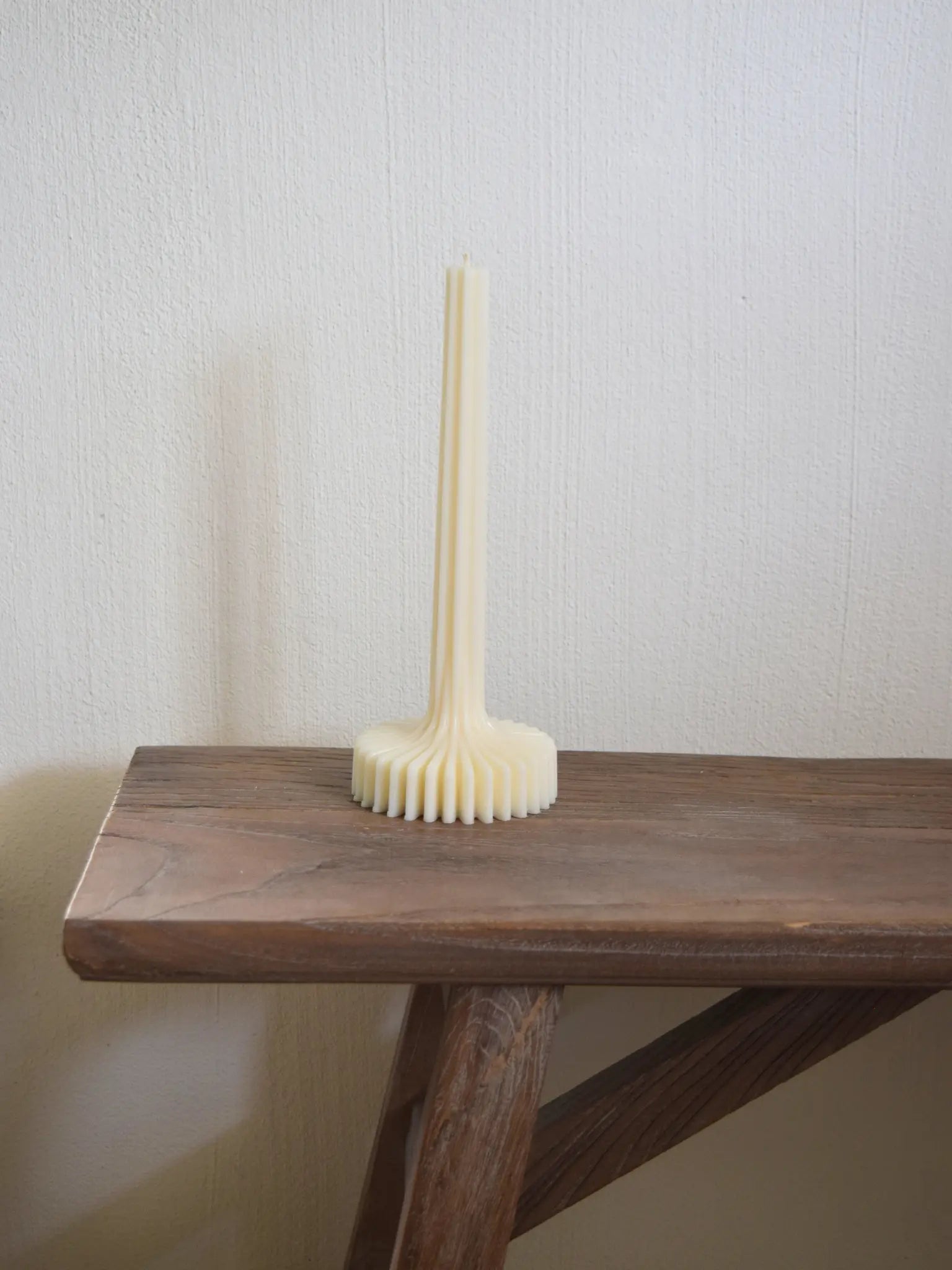 Stabkerze mit Sockel auf einer Bank vor weissem Hintergrund