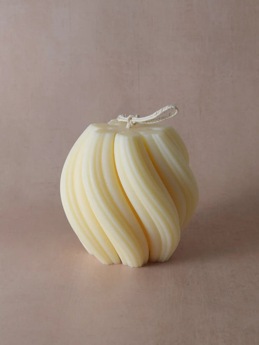 Kerze mit spiralförmiger Struktur vor einem beigen Hintergrund.