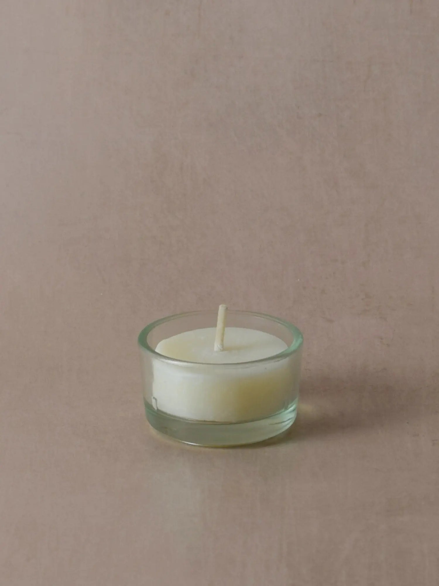 Teelichthülle aus Recyclingglas mit einem Teelicht vor einem beigen Hintergrund
