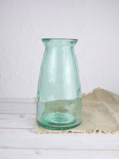 Bläuliche, grosse Vase auf einem braunen Tuch vor einem weissen Hintergrund