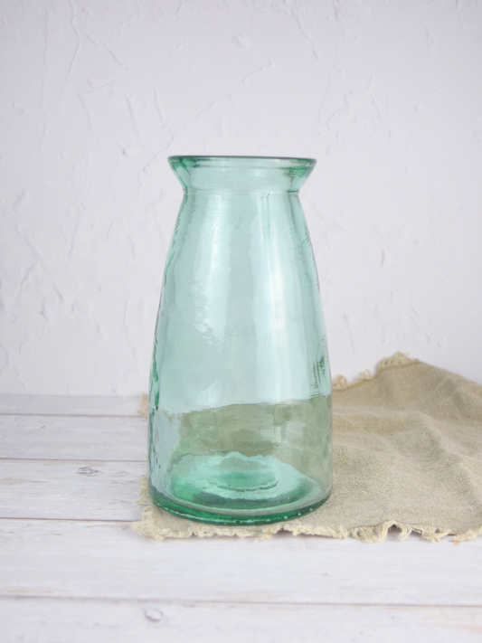 Bläuliche, grosse Vase auf einem braunen Tuch vor einem weissen Hintergrund