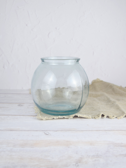 Durchsichtige, runde Vase auf einem braunen Tuch vor einem weissen Hintergrund