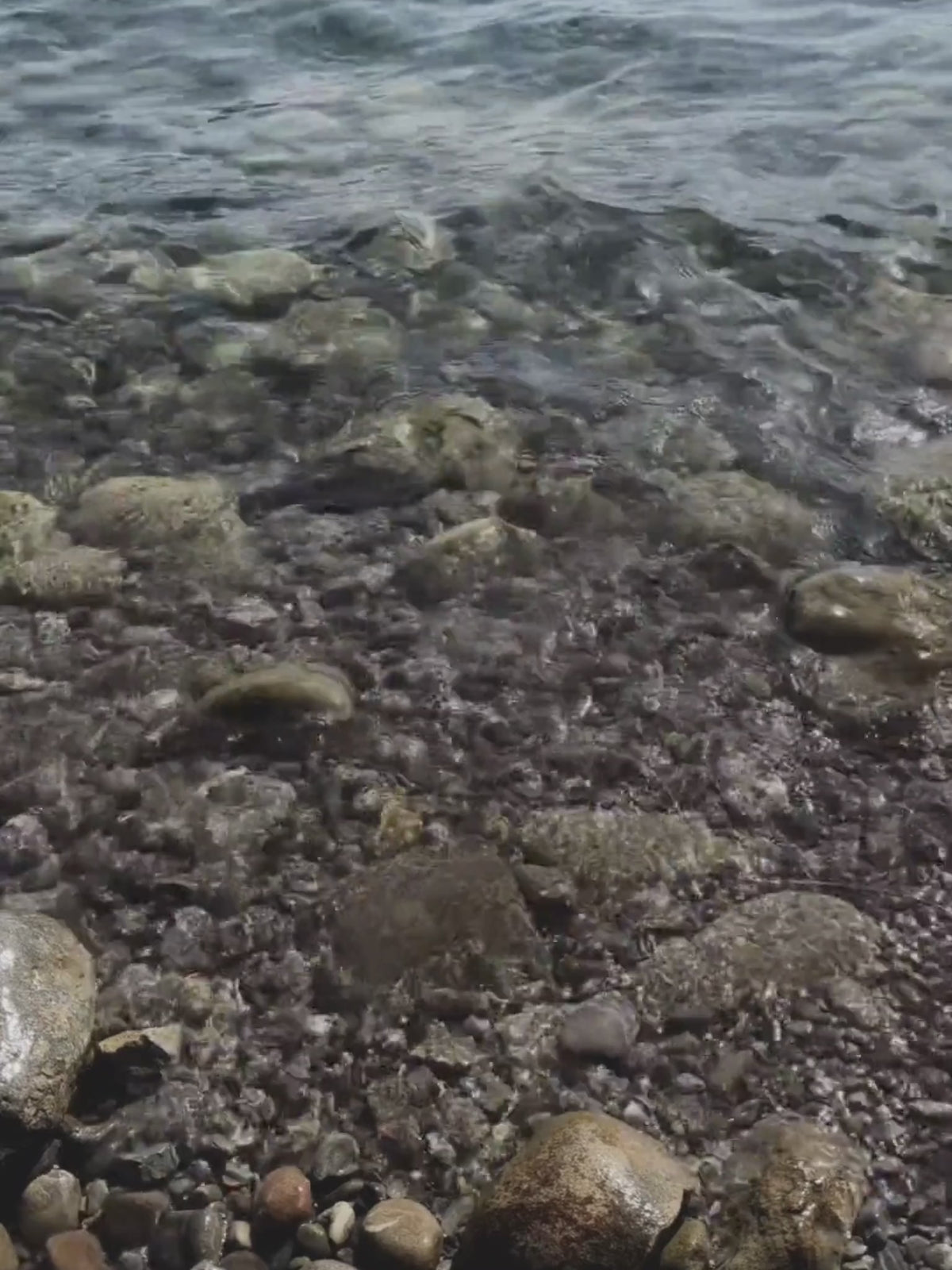 Wellen am See die über Steine fliessen
